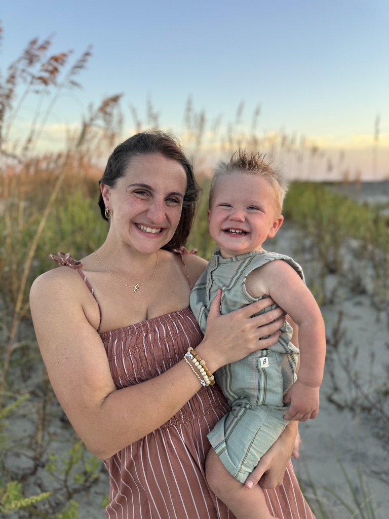 Rachel and a smiling toddler among beach dunes